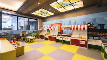 A children's play area with colorful play mats, a play kitchen, and a toy store.