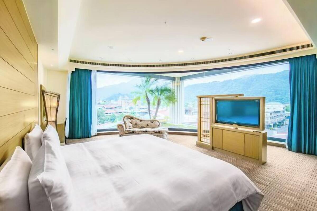 Una habitación de hotel con una cama grande, televisión y vistas a las montañas.
