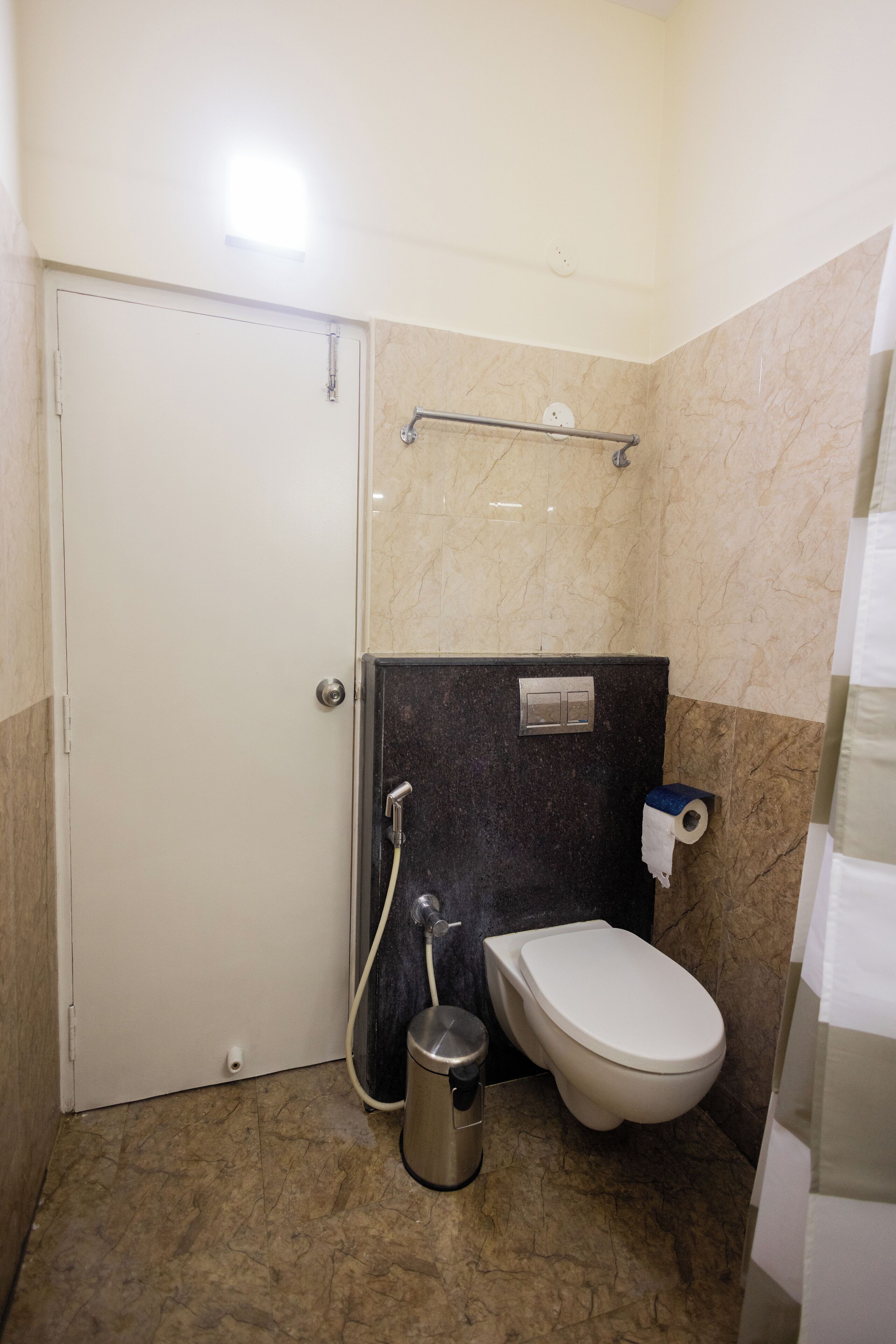 Une petite salle de bain comprenant des toilettes, une poubelle, un porte-serviettes et une douche.