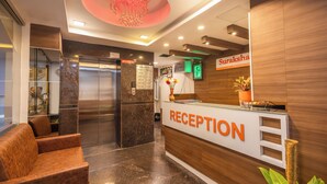 A reception area with a marble floor, a reception desk, a chandelier, and a sign that reads "Suraksha". - Suraksha Stay Brookfield  (Bengaluru)