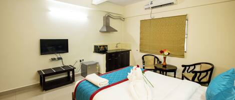 Habitación de hotel con cama, televisor, escritorio, silla y aire acondicionado.