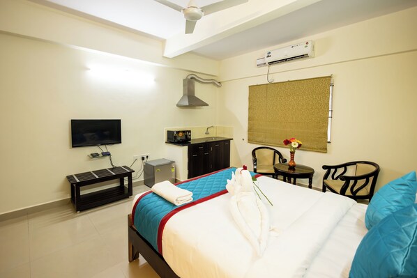 Habitación de hotel con cama, televisor, escritorio, silla y aire acondicionado.