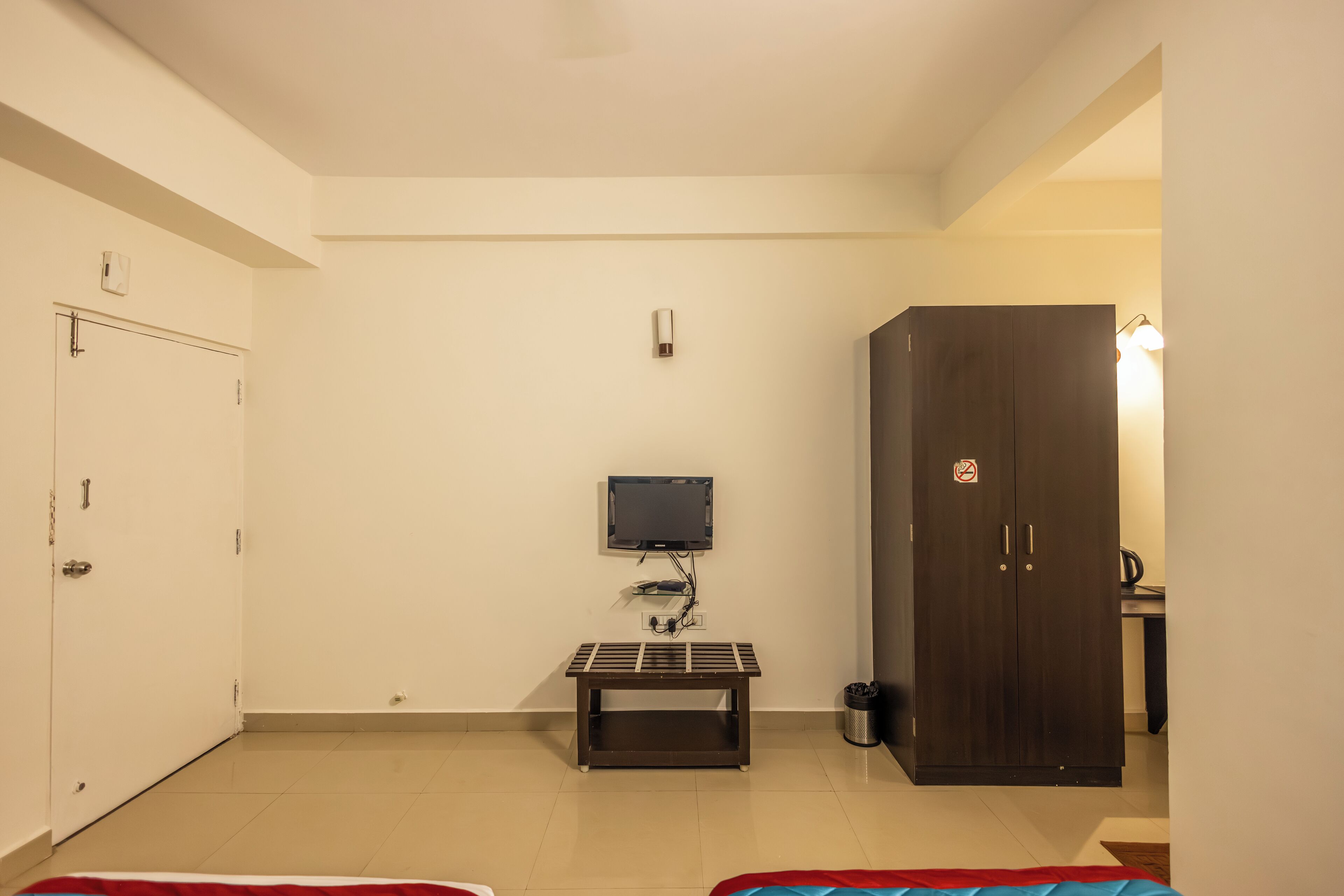 Una habitación con cama, escritorio, armario, televisor y una mesita.