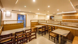 A restaurant with booths and tables, wooden paneling, and recessed ceiling lights. - Suraksha Stay Brookfield  (Bengaluru)