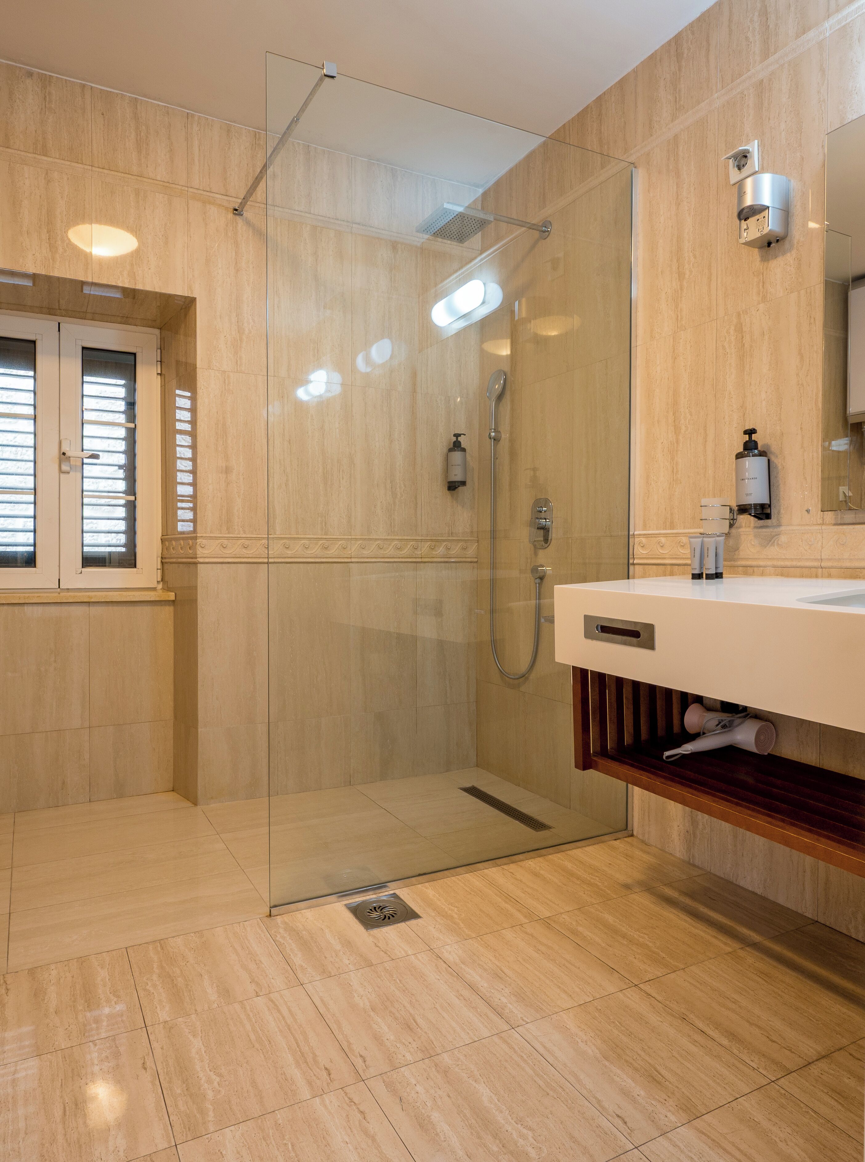 A modern bathroom with a glass-enclosed shower, a vanity with a mirror, and a built-in shelf.