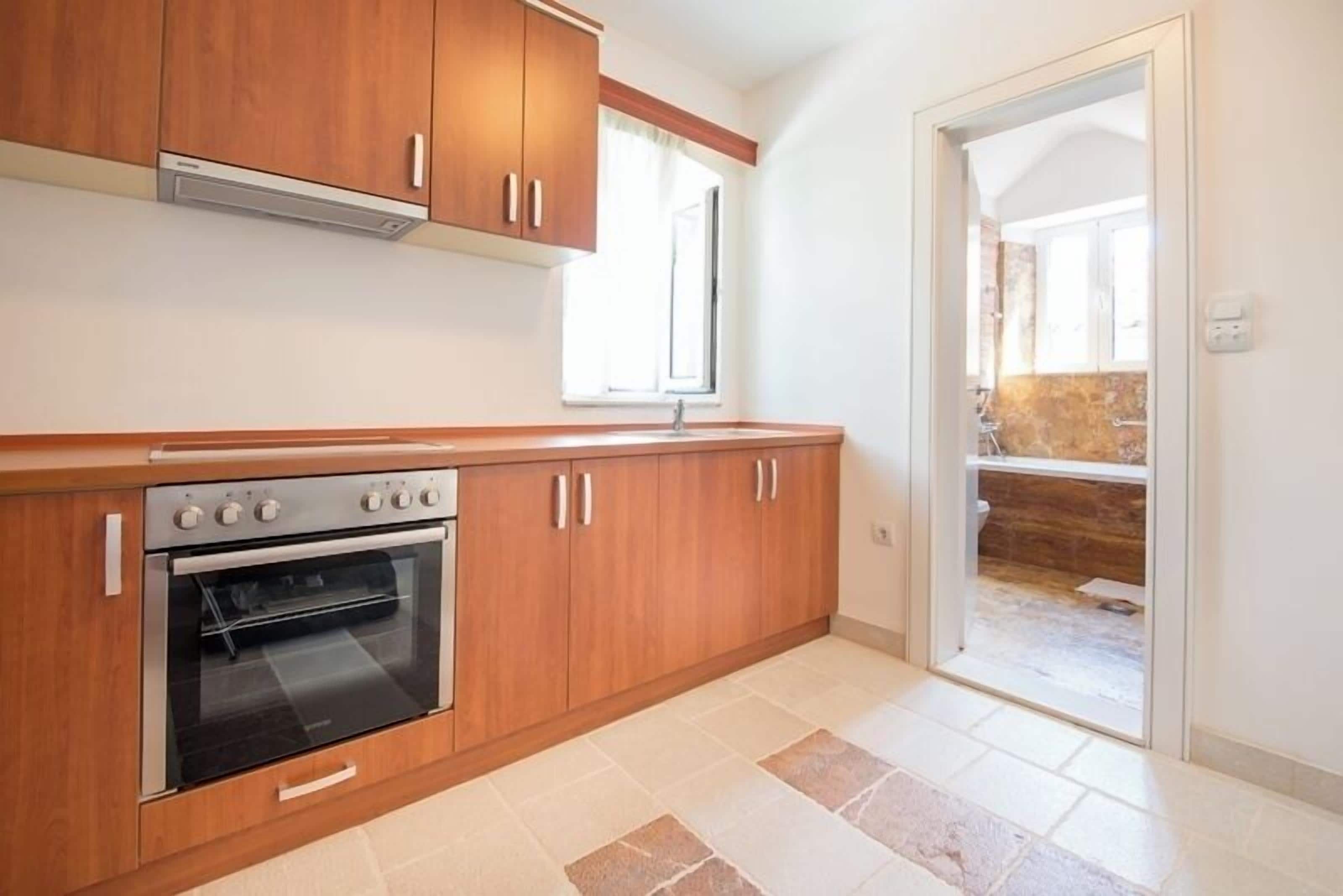 A kitchen with wooden cabinets, a built-in oven, and a window.