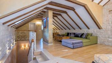 Ein Dachzimmer mit freiliegenden Holzbalken, einer Steinwand, einem grünen Sofa und einem Holzboden.