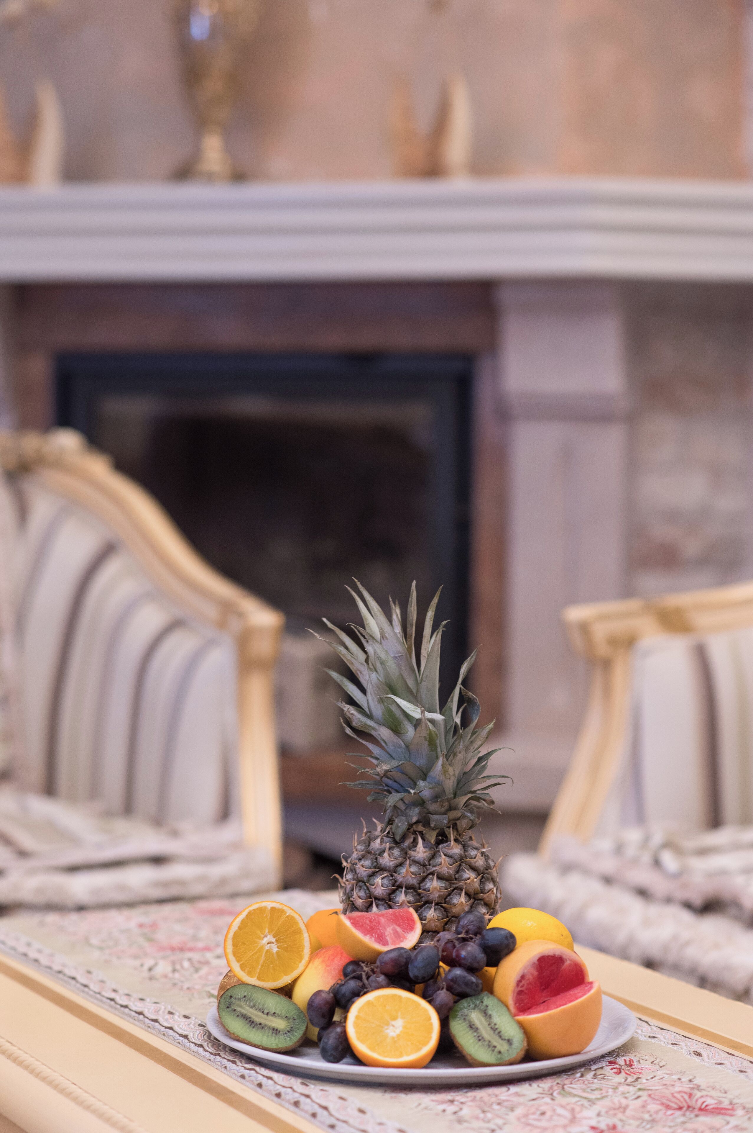 A fruit platter on a table with a fireplace in the background.