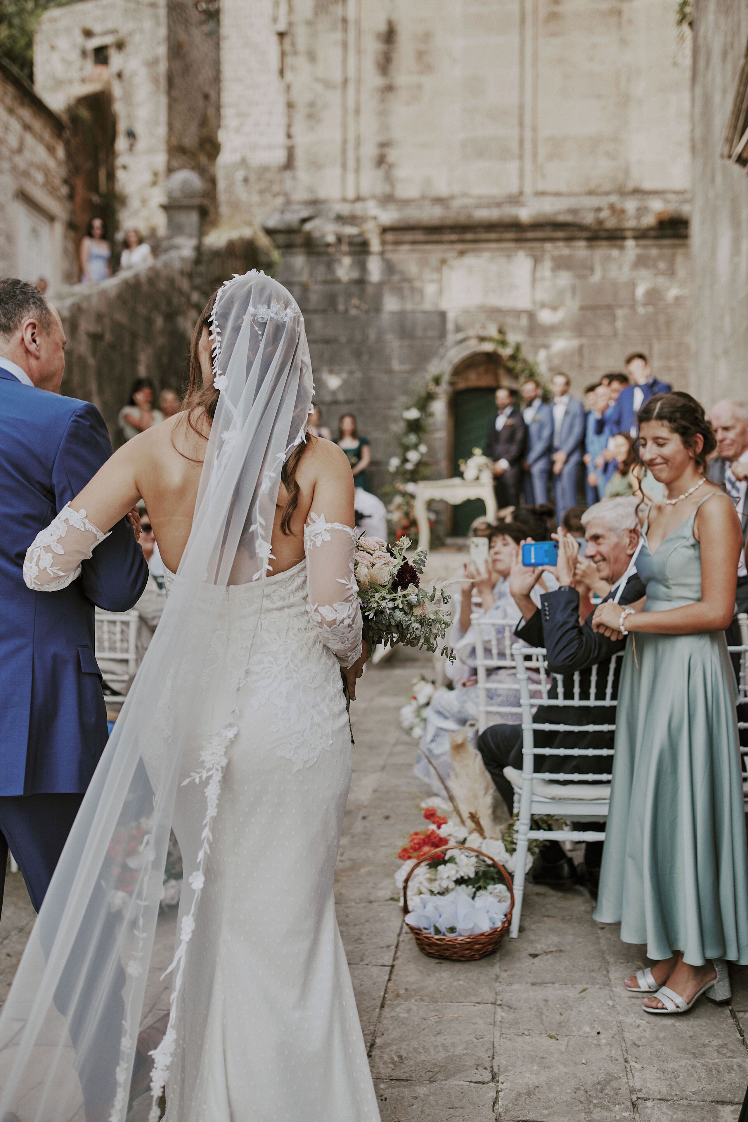 A wedding ceremony in an outdoor setting with stone architecture.