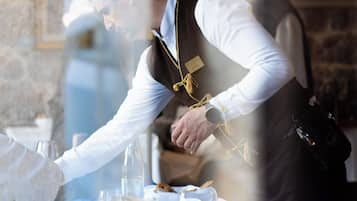 A waiter serving a meal at a table with a stone wall background.