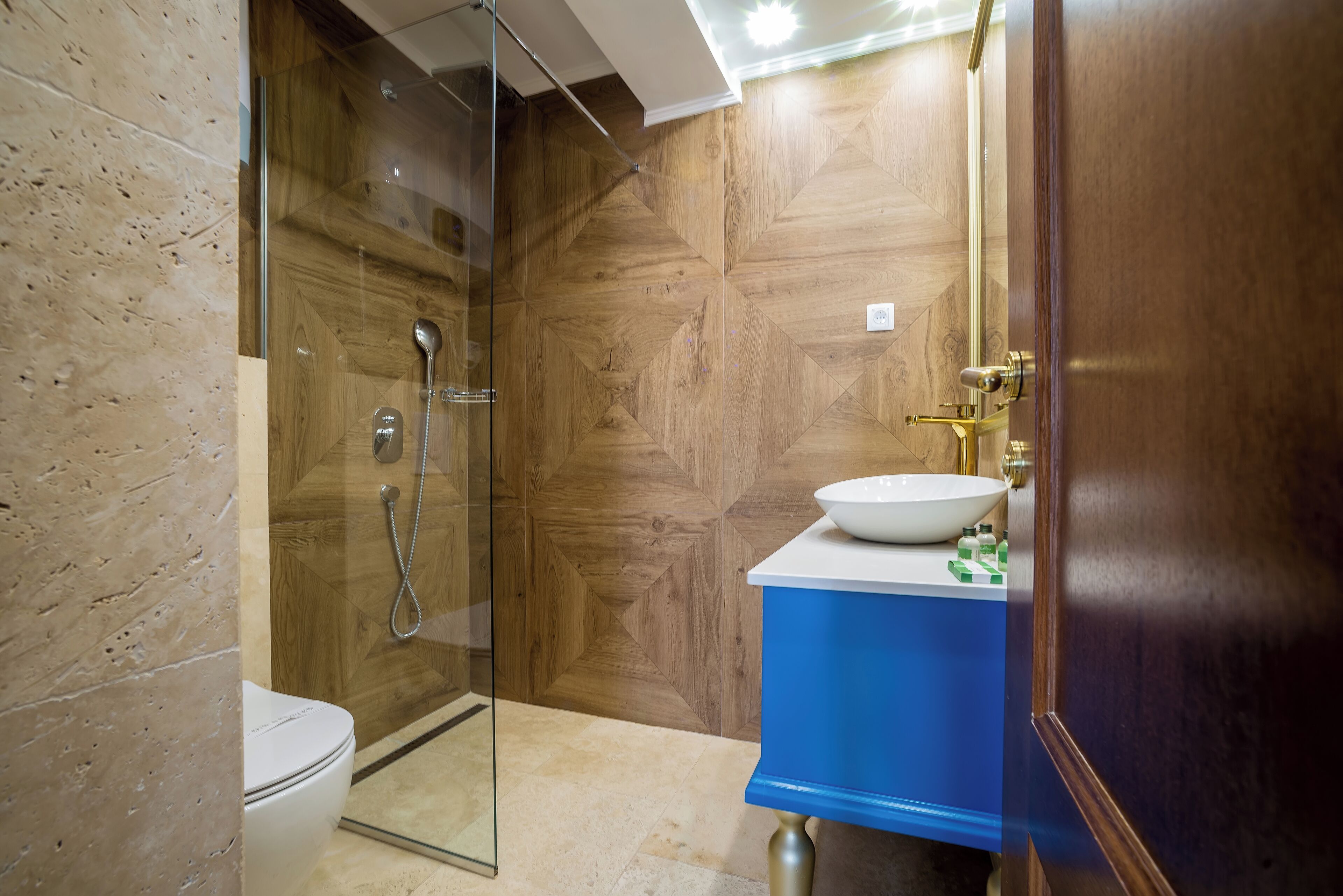 A modern bathroom with a glass-enclosed shower, a white toilet, and a blue sink with a white basin.