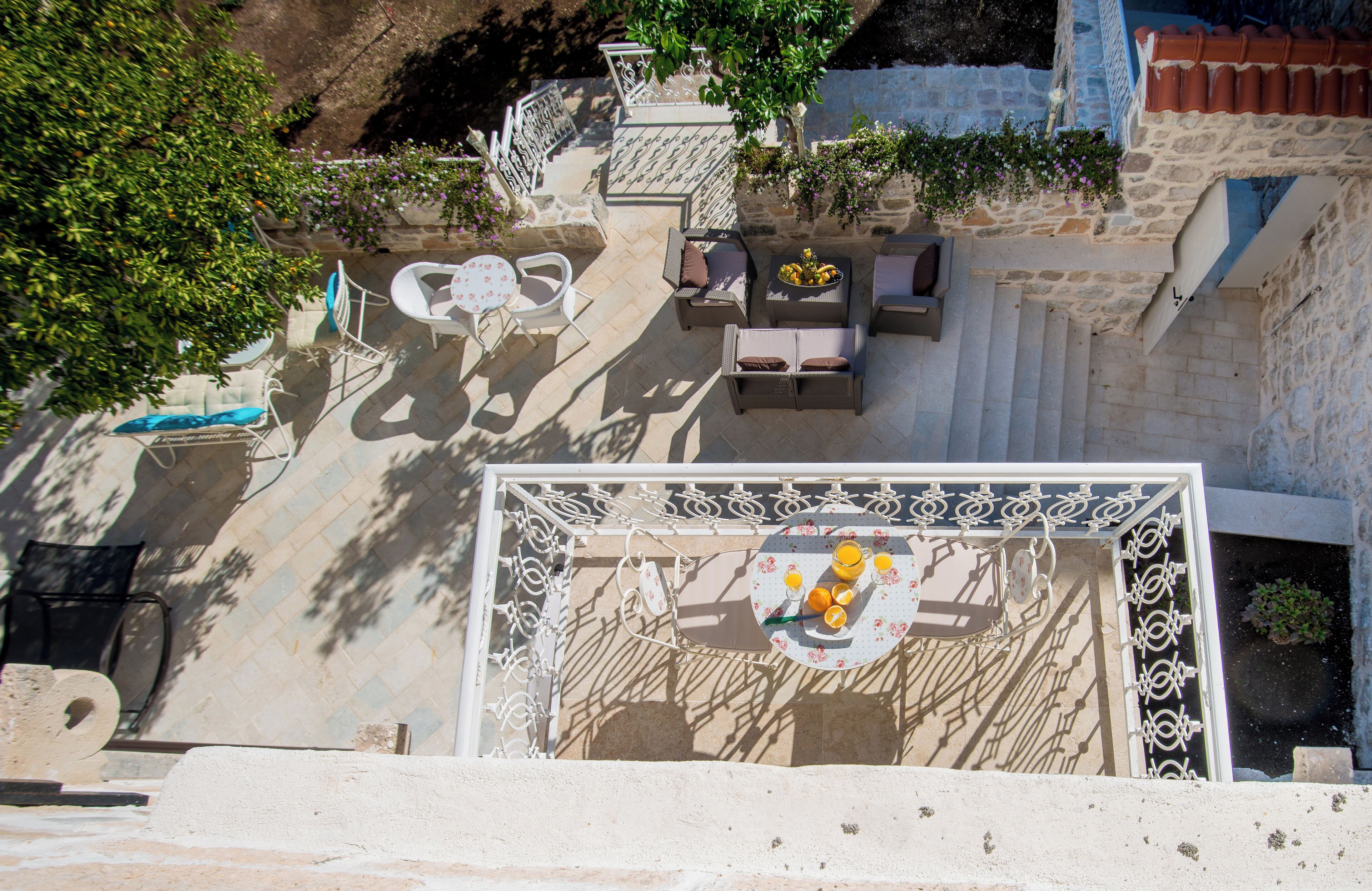 A rooftop terrace with outdoor furniture, a dining table with fruit, and a view of the surrounding architecture.
