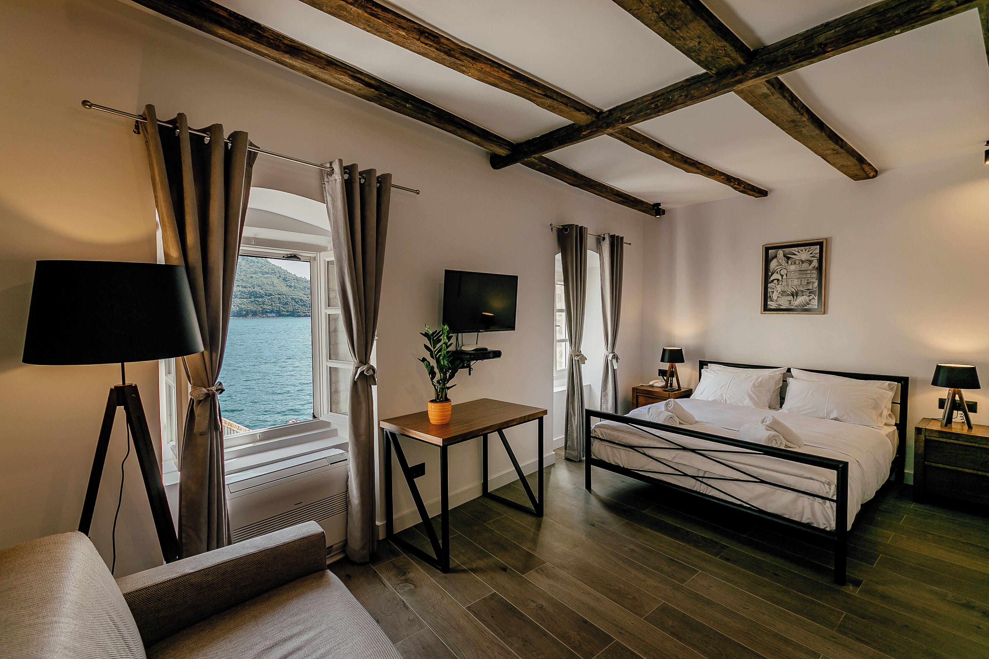 A bedroom with a bed, bedside tables, a TV, and a window with curtains.
