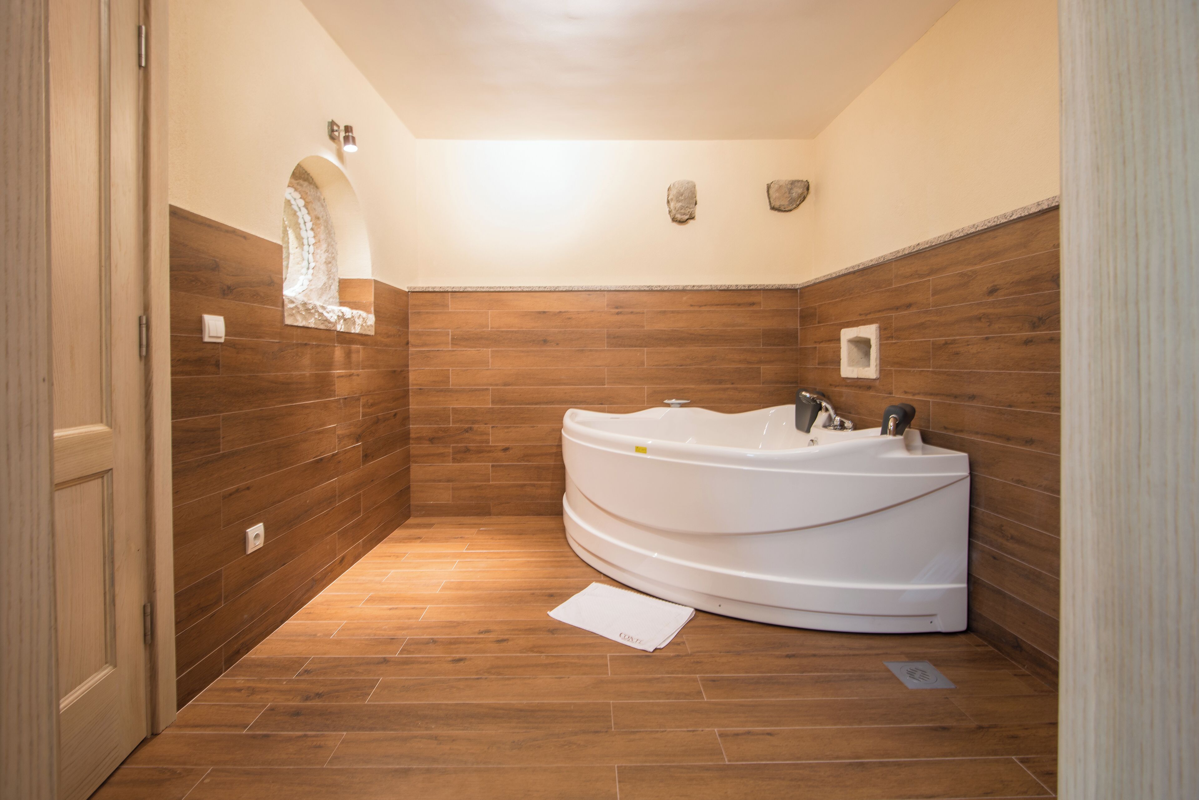 A modern bathroom with a freestanding bathtub, wooden paneling, and a small mirror with a decorative frame.