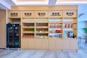 Área de recepção de hotel com seções identificadas para bebidas frias, lanches, livros, informações completas e chás.