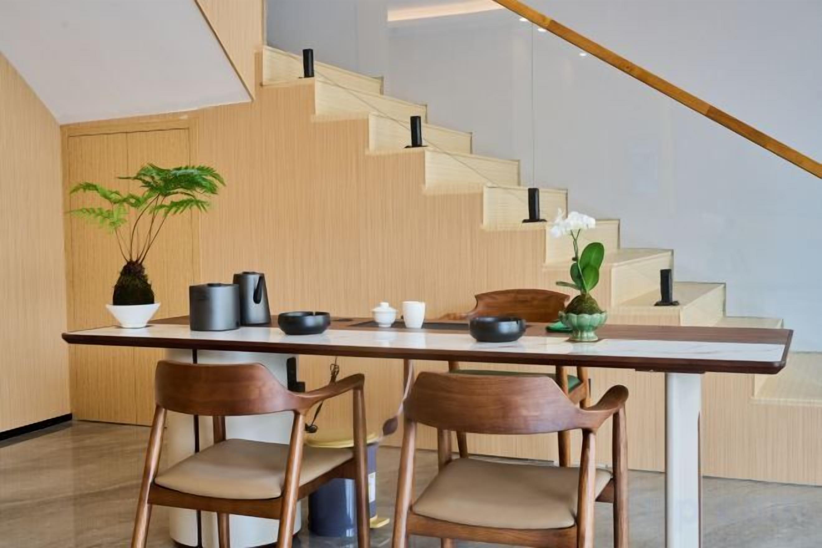 Eine moderne Küche mit Holztisch und -stühlen, einer Treppe und einem Blumentopf.
