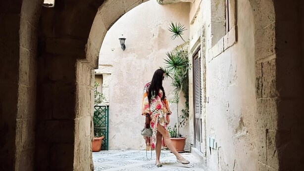An arched corridor with a tiled floor, leading to a building with a window and a door. - Elsa D'ortigia (Syracuse)