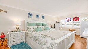 A bedroom with a bed, nightstands, a dresser, and a window with blinds.