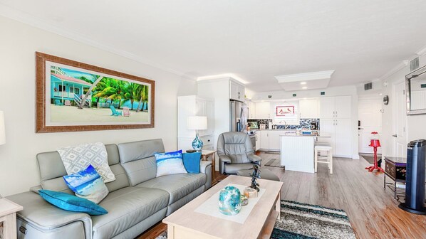 A modern living room with a grey sofa, a coffee table, and a painting of a beach scene.