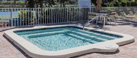 Una piscina rectangular con una escalera de seguridad, rodeada por una valla de metal blanco, y un cartel que indica una profundidad máxima de 7 pies.