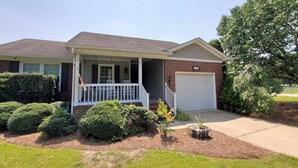 A two-story house with a front porch, a garage, and a well-maintained lawn.