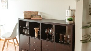 Een moderne woonkamer met een donker houten kast, een witte stoel en een kleine potplant.