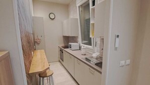 A compact kitchen with a wooden table, a microwave, and a window. - Marina Romea 2 Splitted Executive Flats (Ravenna)