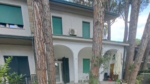 A pathway leading to a building with a covered patio area, surrounded by trees and a gravel area. - Marina Romea 2 Splitted Executive Flats (Ravenna)