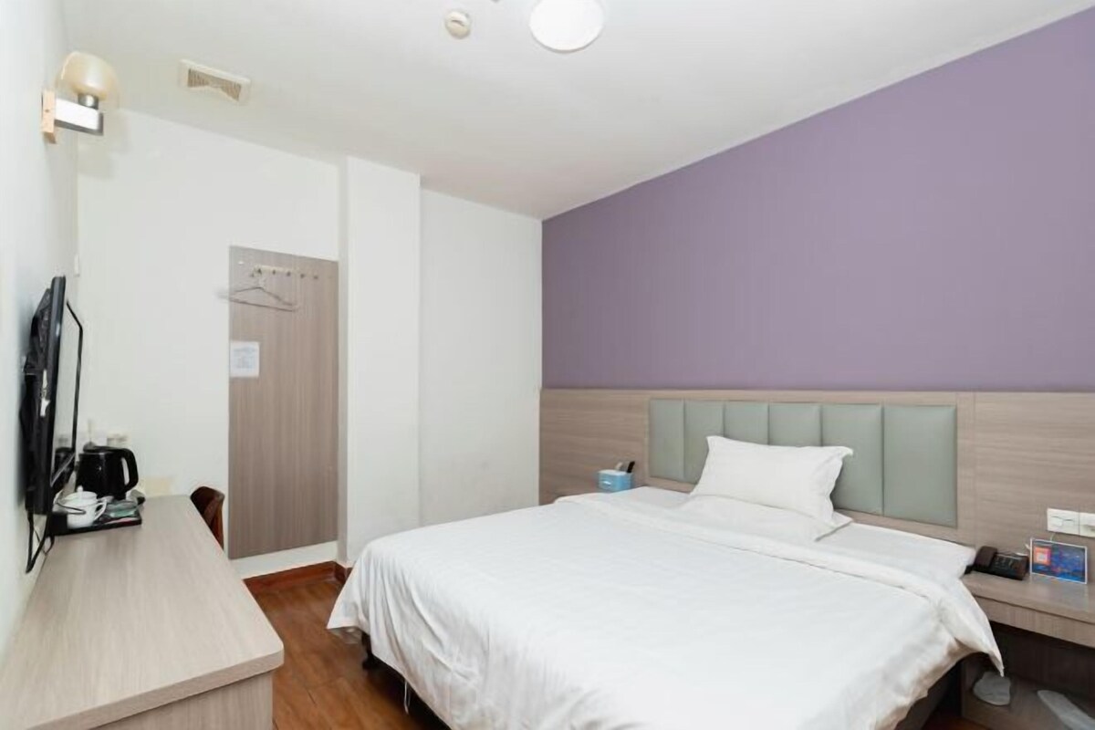 Quarto de hotel com cama, mesa de cabeceira e escrivaninha com cadeira.