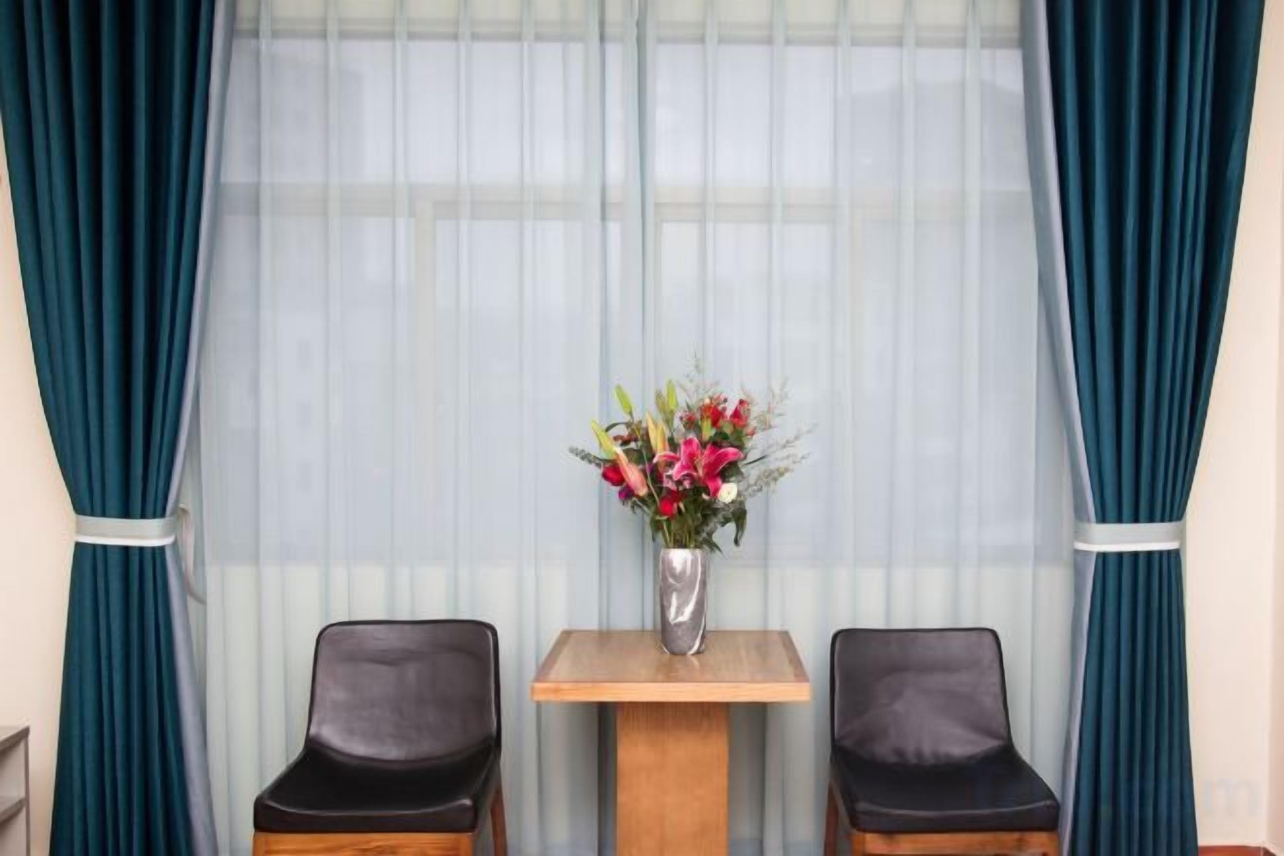 Een kamer met twee stoelen, een tafeltje en een bloevas.