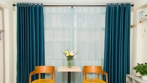 A room with teal curtains, a small table with a vase of flowers, and two yellow chairs. - Shenzhen Liuliu Hotel (Shiyan Bus Station) (Shenzhen)