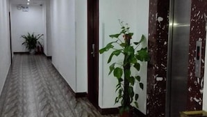 A hallway with a marble floor, a potted plant, and a door with a marble wall. - Shenzhen Liuliu Hotel (Shiyan Bus Station) (Shenzhen)