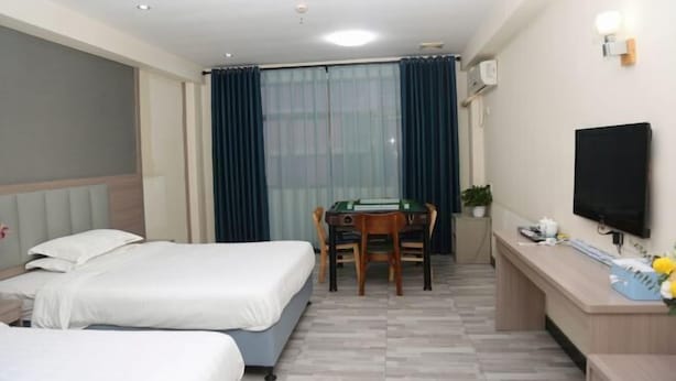 A hotel room with two beds, a desk with a computer, a television, and a window with curtains. - Shenzhen Liuliu Hotel (Shiyan Bus Station) (Shenzhen)
