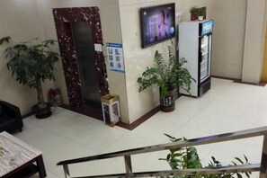 A reception area with a marble reception desk, a television mounted on the wall, a refrigerator, and potted plants. - Shenzhen Liuliu Hotel (Shiyan Bus Station) (Shenzhen)