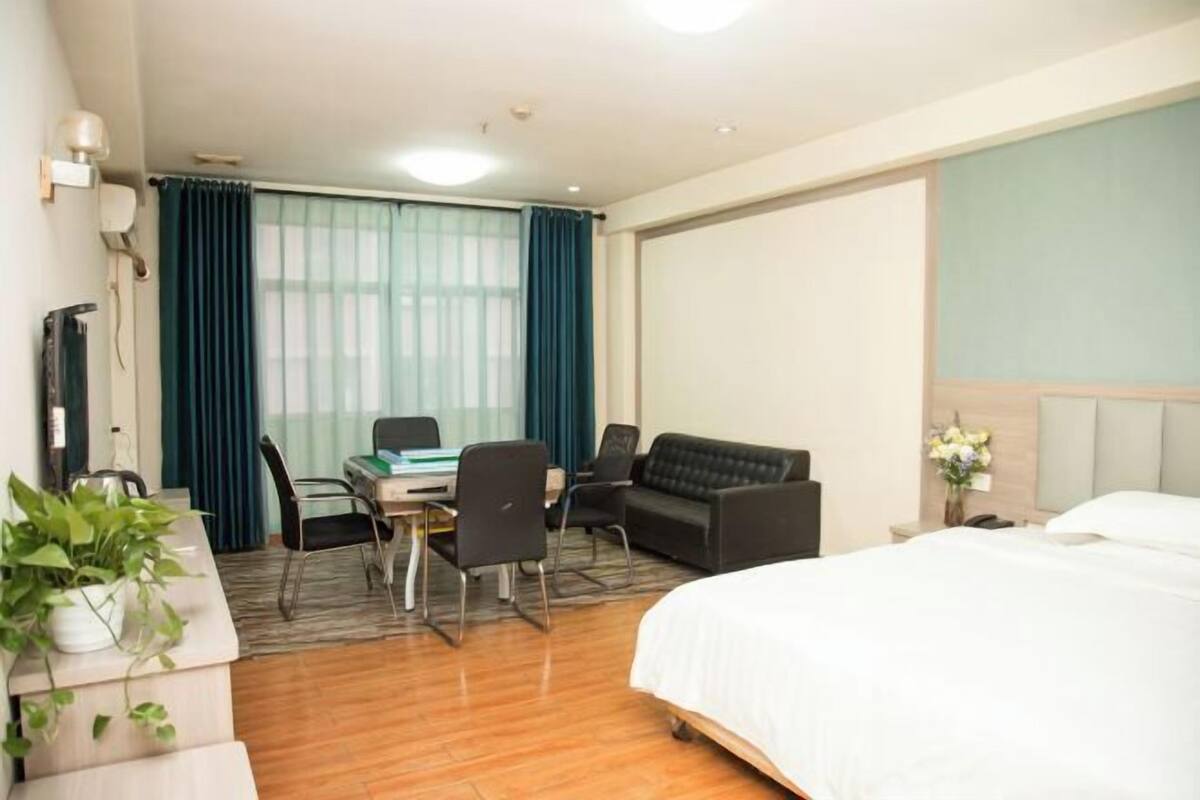 A hotel room with a bed, a desk with a chair, a sofa, and a TV.