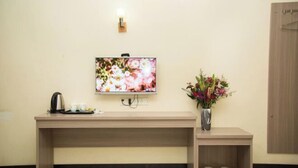 A reception desk with a flat-screen TV, a vase with flowers, and a kettle. - Shenzhen Liuliu Hotel (Shiyan Bus Station) (Shenzhen)