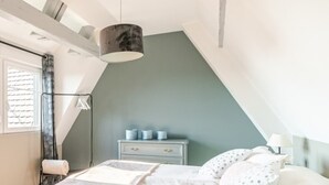 Een slaapkamer met een bed, nachtkastje en hanglamp.