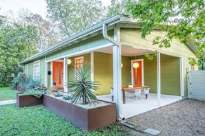 Una casa moderna con un porche cubierto, comedor y un jardín cuidado.