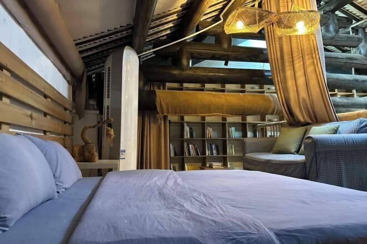 Una habitación acogedora con una cama, una estantería y una silla de mimbre.