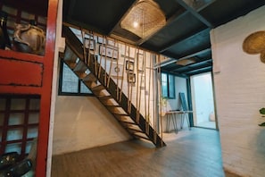 Un escalier avec une rampe en bois et un luminaire tressé placé au-dessus.