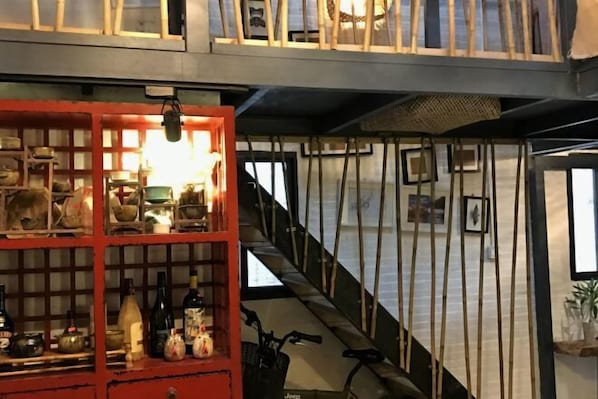 Un escalier avec une rampe en bois, un meuble rouge contenant divers objets et un vélo.