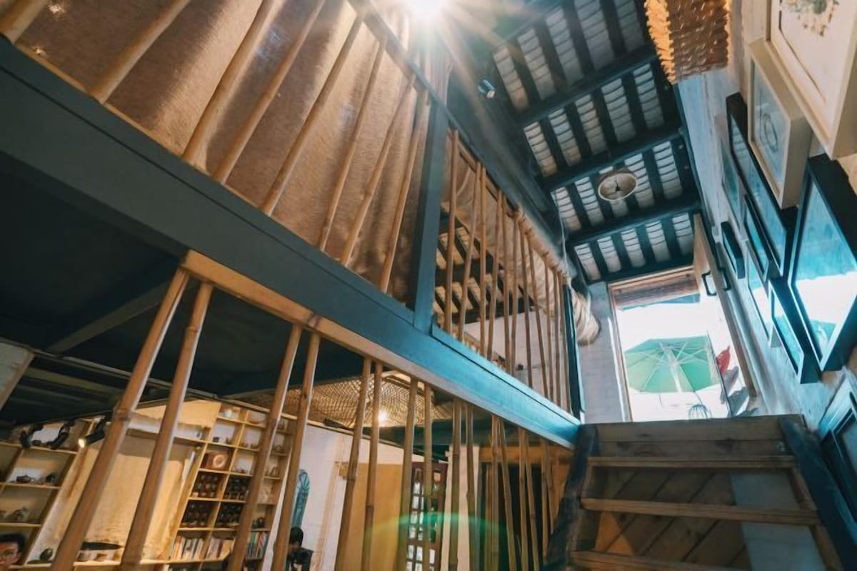 Un intérieur à plusieurs niveaux avec des poutres en bois, un escalier et une vue sur l’extérieur.