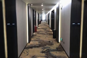 Pasillo de hotel con puertas numeradas 1317 y 1304, alfombrado con un diseño y equipado con letreros de salida de emergencia.