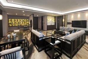 A modern living room with a sofa set, a dining table, and a TV mounted on the wall. - Huilai Hotel (Huilai)