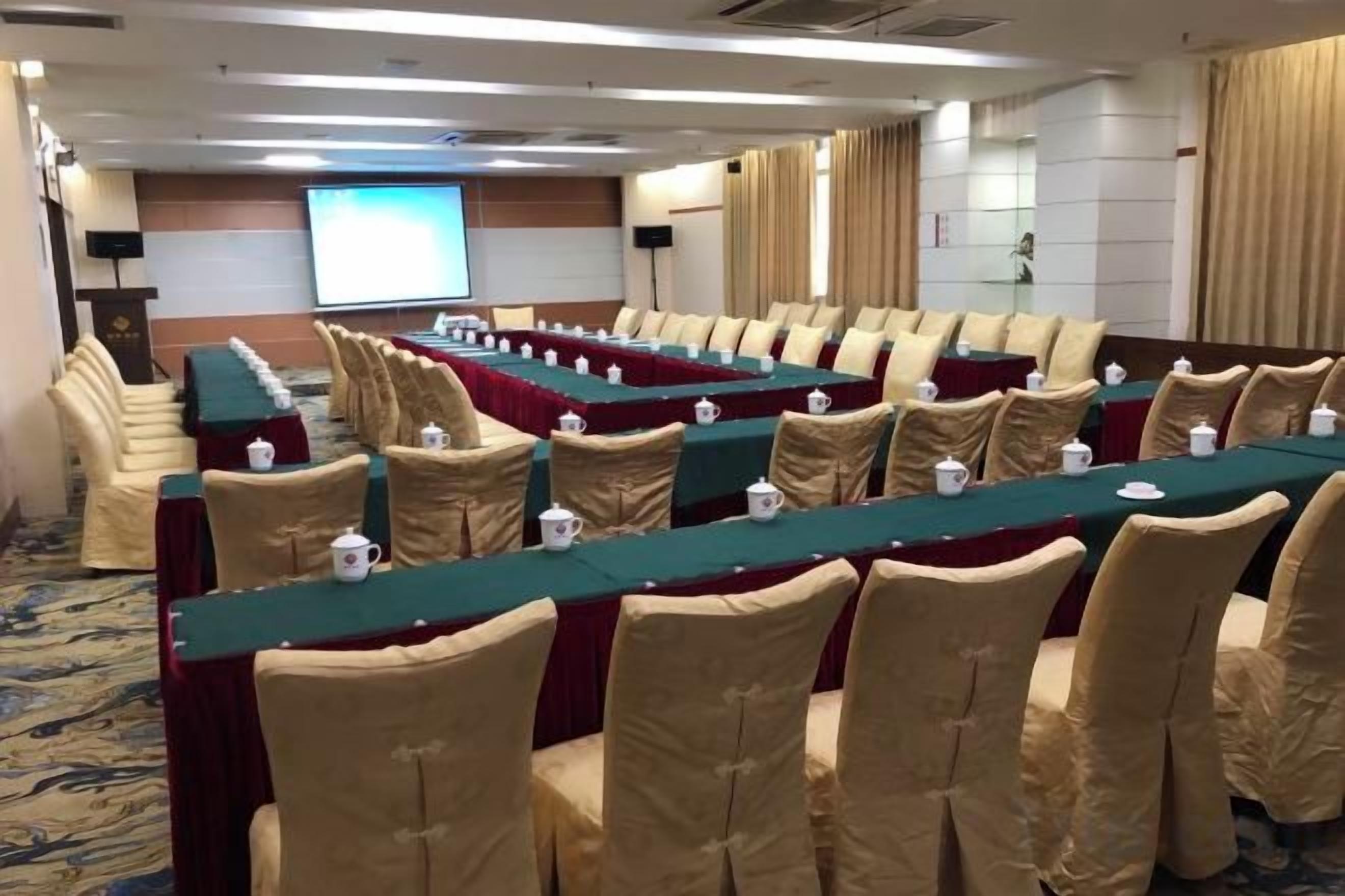 A conference room with long tables, chairs, and a projection screen.