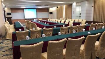 A conference room with long tables, chairs, and a projection screen.