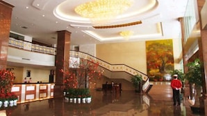 Eine großzügige Lobby mit einer imposanten Treppe, einer Rezeption und einer großen Chandelier.