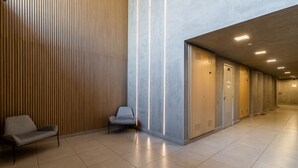 Ein moderner Flur mit einer Wand aus Holzleisten, einer grauen Bank und einer Reihe von Schließfächern.