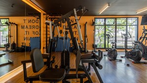 Ein Fitnessstudio mit Trainingsgeräten, großen Fenstern und Holzboden.