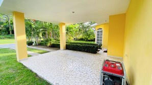 A covered outdoor area with a tiled floor, yellow walls, and a red object on the right.
